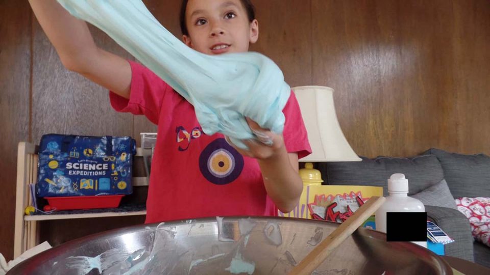 A child playing with blue fluffy slime