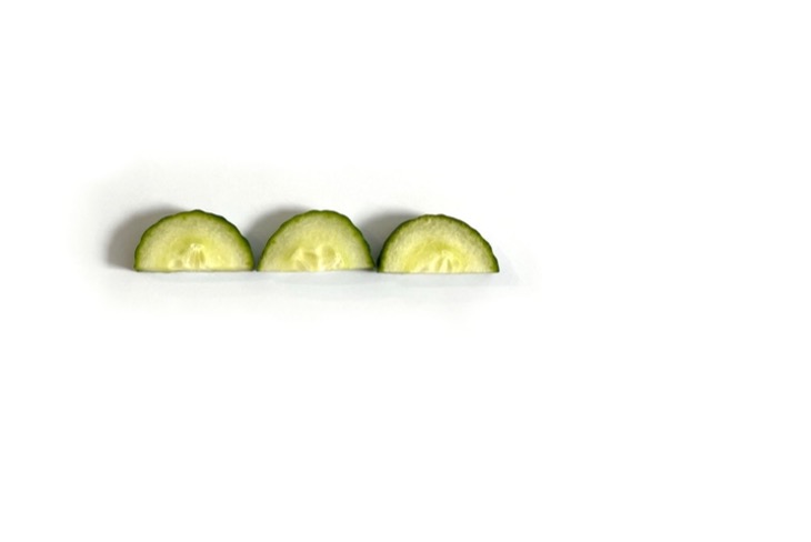 Three half cucumber slices in a row